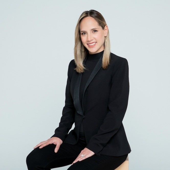 Portrait of Camila Zuluaga in black suit against pale blue grey background