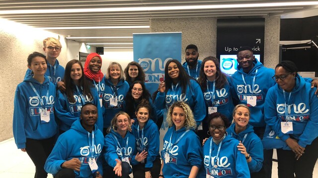 Photo de groupe des volontaires de One Young World portant des sweats à capuche bleus griffés