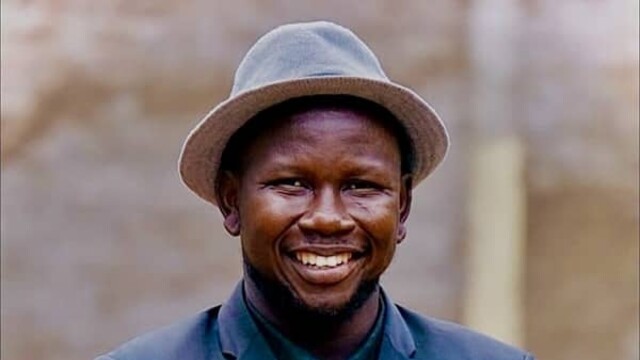 Elihu Jos Benam in dark blue blazer and hat