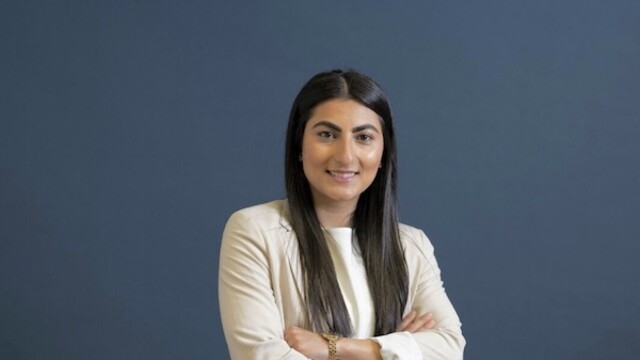 Farkhunda Muhtaj portrait photo wearing long beige overcoat against dark blue background