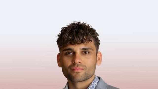 Justin Langan in grey suit against red and white background