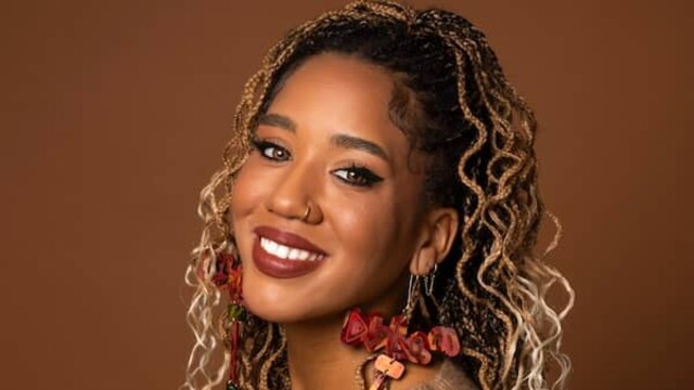 Larissa Crawford portrait wearing light brown top against darker brown background