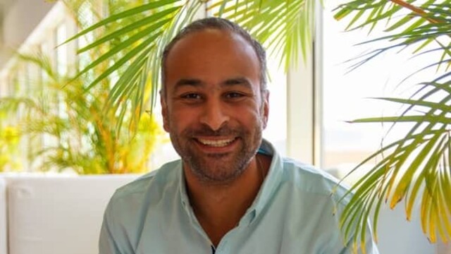 Seif Taher in casual light green shirt against a background of white sofa and indoor plants