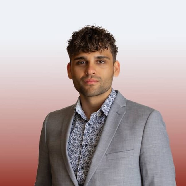 Justin Langan in grey suit against red and white background