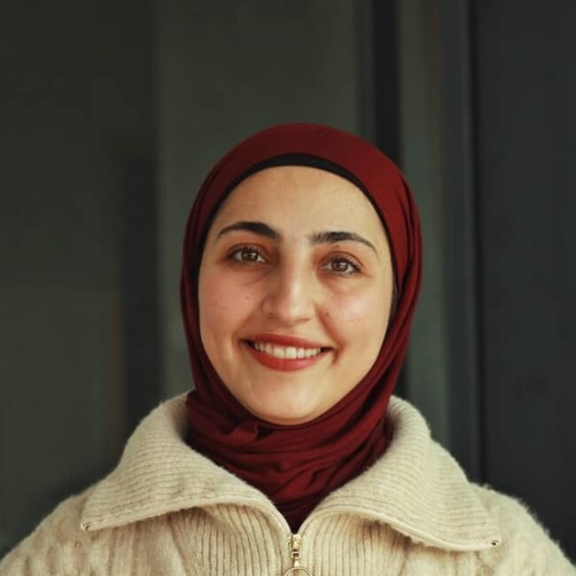 Lama Amro avec un foulard marron sur fond vert foncé