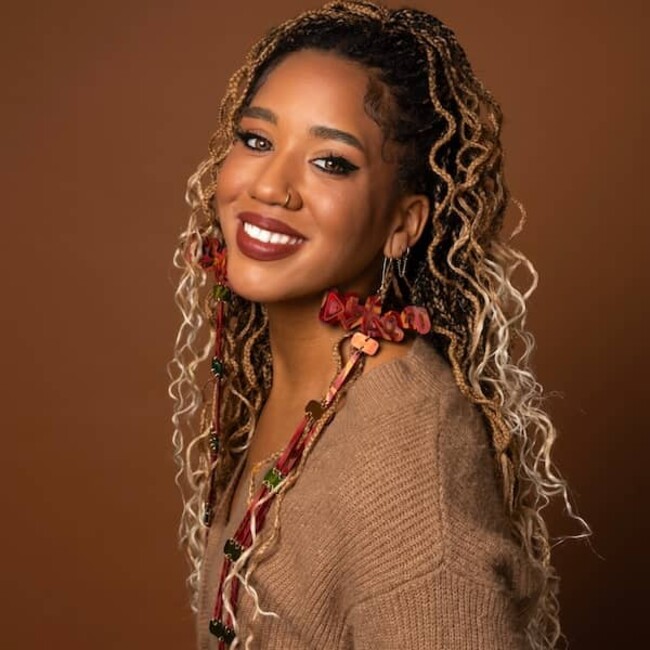 Larissa Crawford portrait wearing light brown top against darker brown background