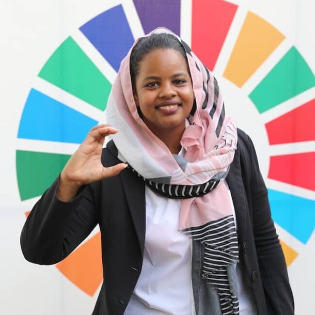 Photo de Nisreen Elsaim contre la roue des couleurs des ODD de l'ONU