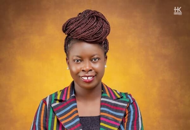 Adenike Oladosu portrait wearing striped colourful jacket against brown yellow background