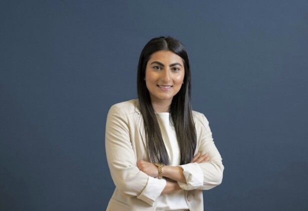 Farkhunda Muhtaj portrait photo wearing long beige overcoat against dark blue background