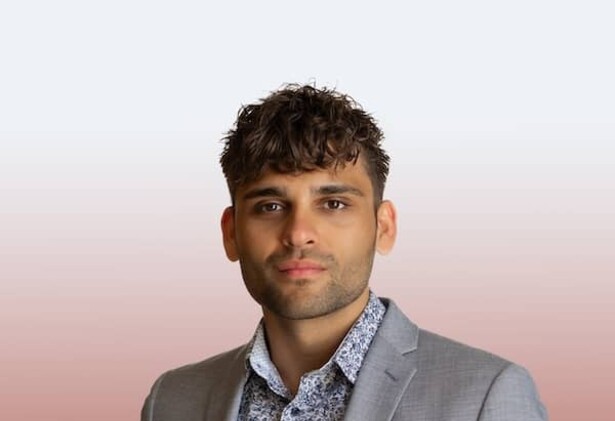 Justin Langan in grey suit against red and white background