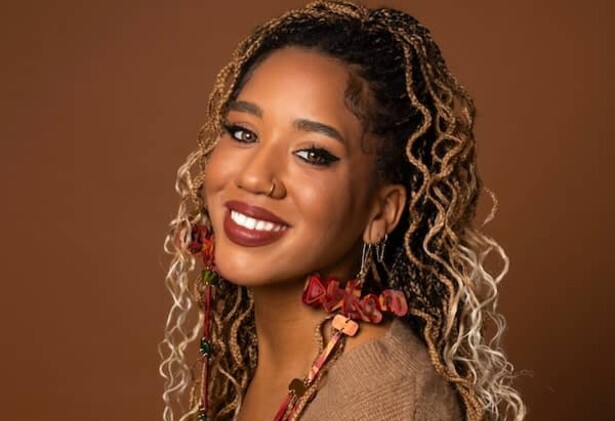 Larissa Crawford portrait wearing light brown top against darker brown background