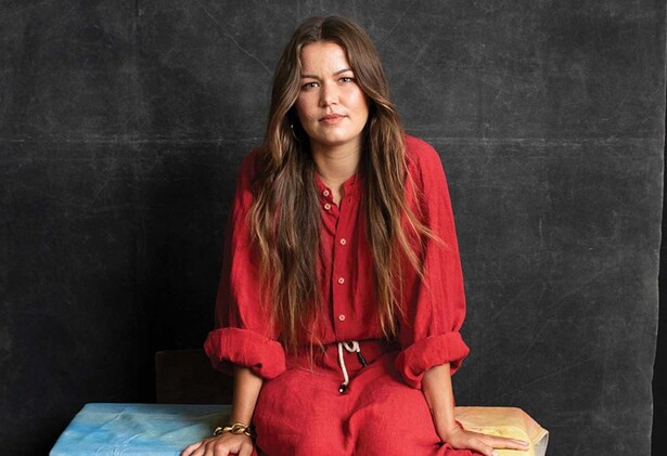 Portrait of Vanessa Turnbull-Roberts in red dress sitting down against black background